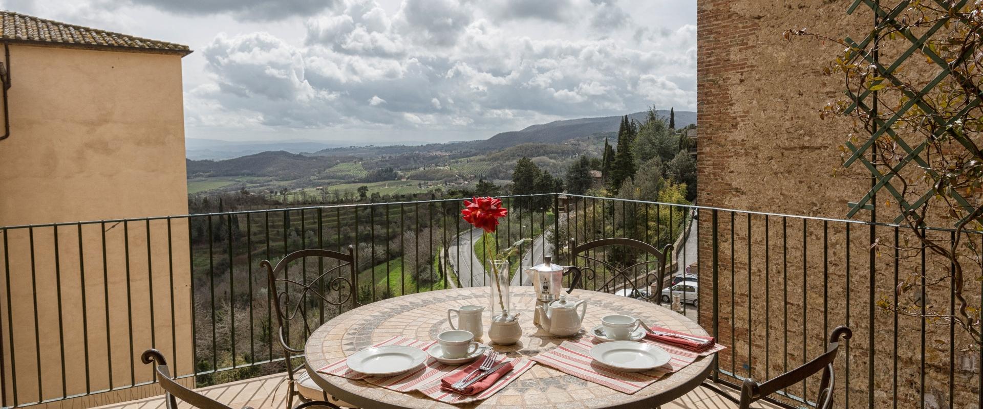 Colazione su terrazza con vista panoramica su colline e cielo nuvoloso.