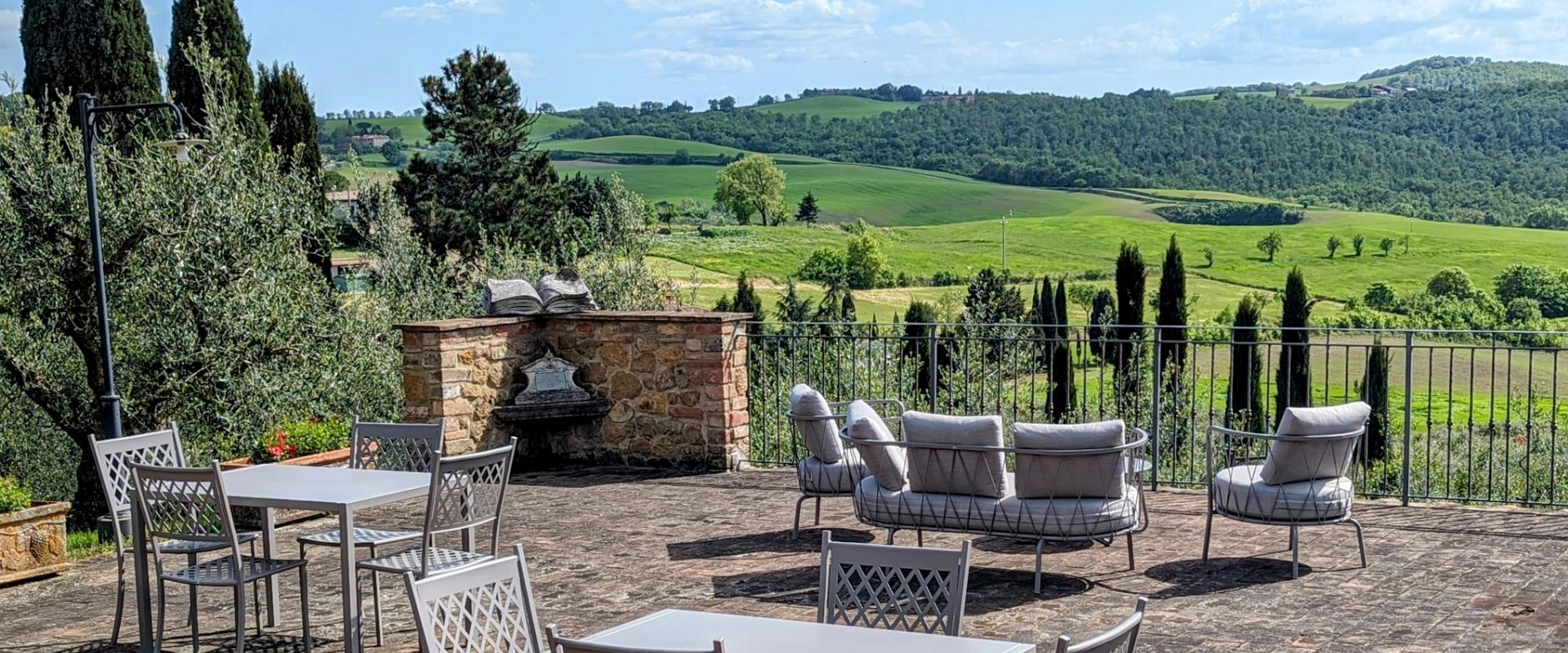Terrazza con vista su colline verdi, tavoli e sedie eleganti.