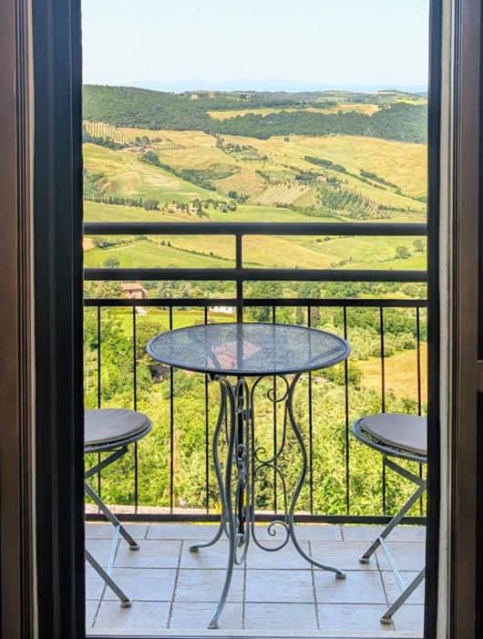 Vista collinare da balcone con tavolino, atmosfera serena e luminosa.