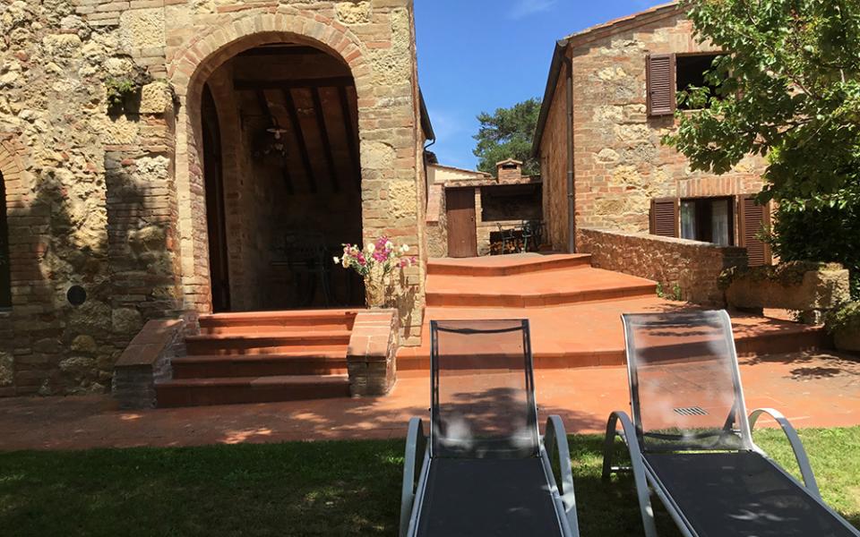 Casale in pietra con sedie a sdraio e giardino, atmosfera rilassante e rustica.