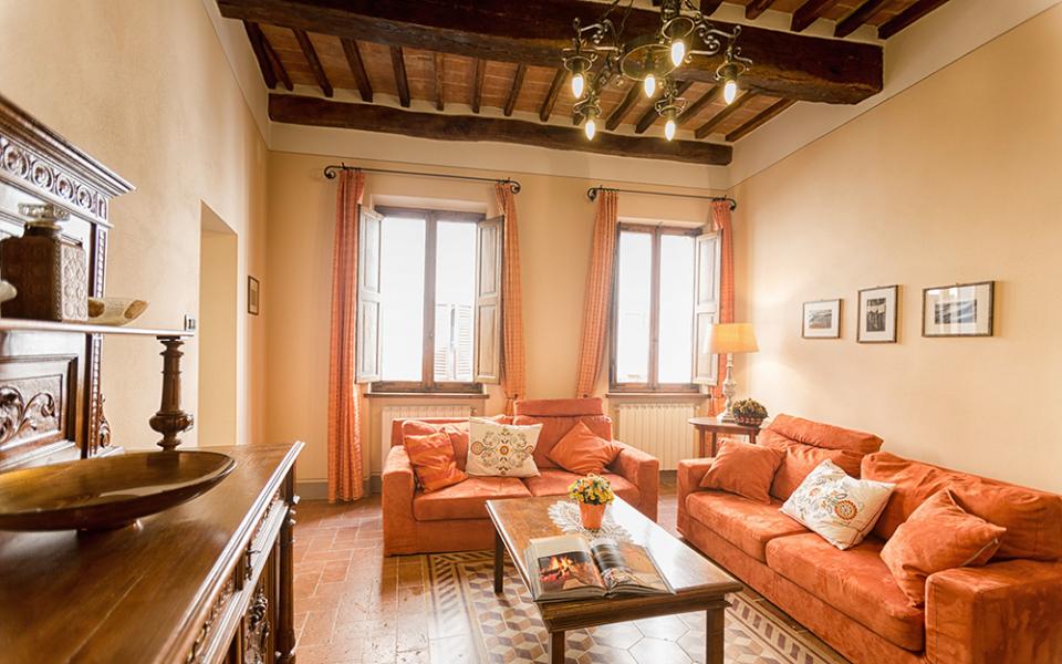 Soggiorno accogliente con divani arancioni, soffitto con travi a vista e arredi in legno.