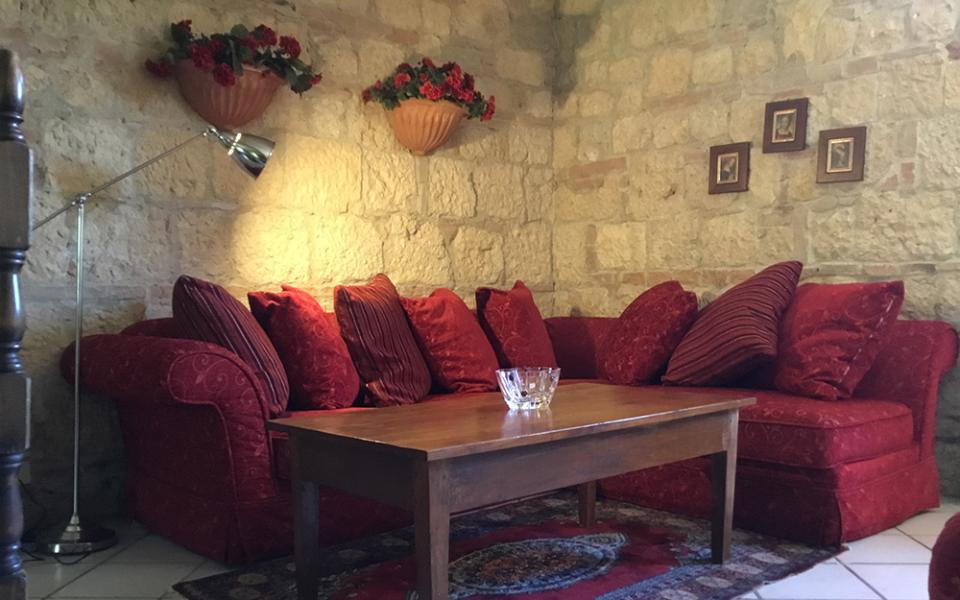 Salotto accogliente con divano rosso, tavolino di legno e decorazioni floreali.