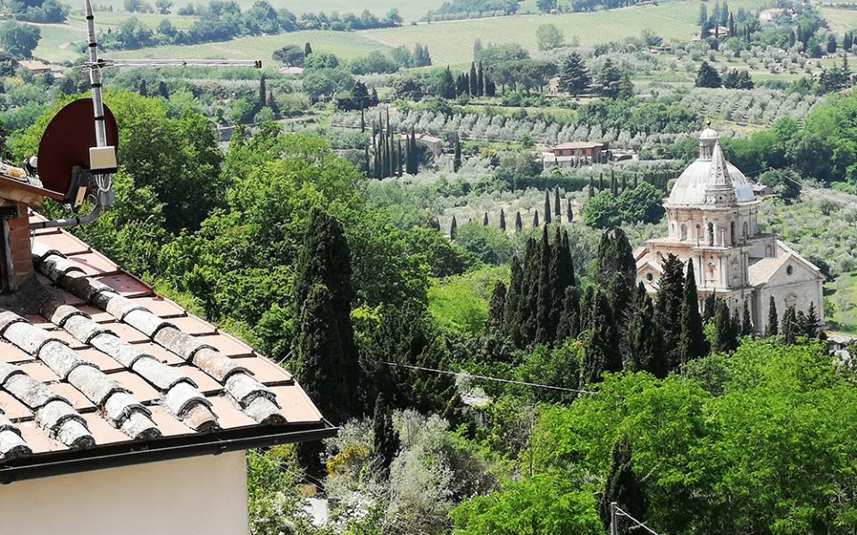 Vista su campagna italiana con chiesa storica e tetti in tegole.