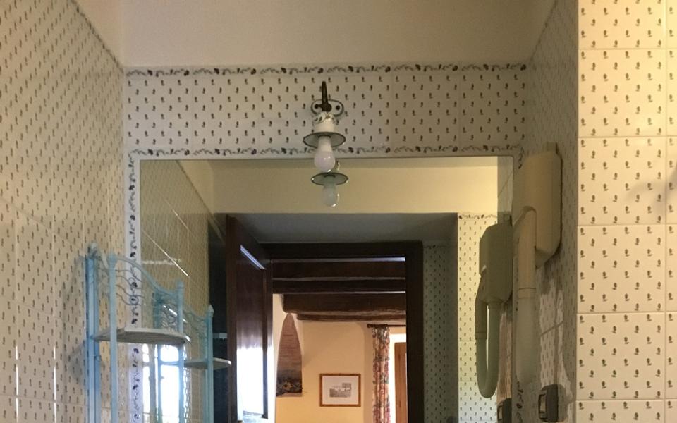 Bagno vintage con piastrelle verdi, lavabo classico e specchio grande.